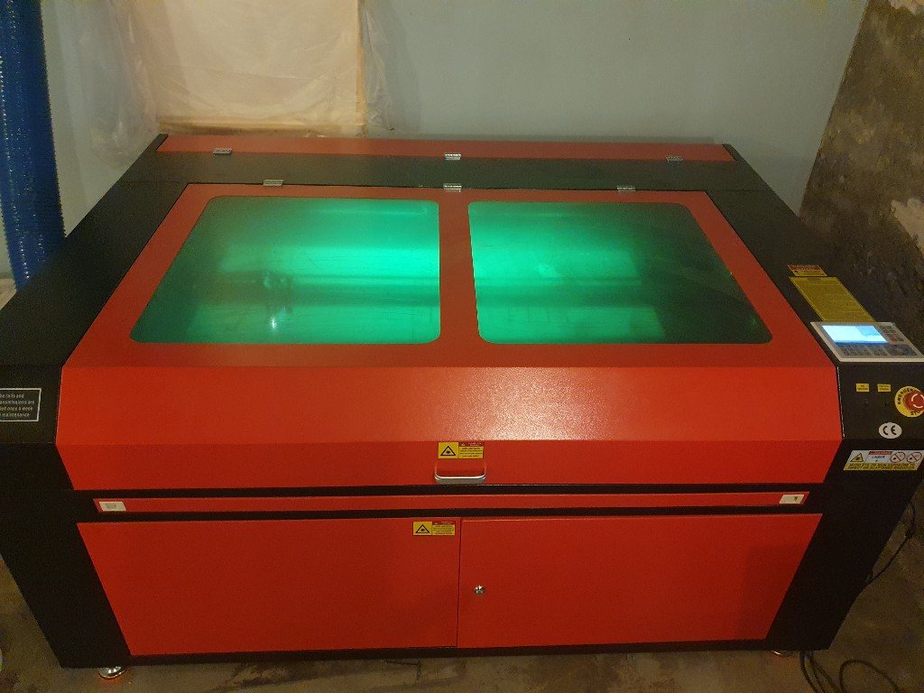 Golvstående röd och svart CO2-laserskärare med gröna skyddsglas och Ruida-panel